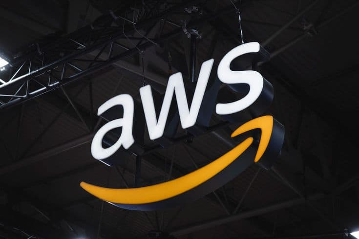 An illuminated AWS sign hanging from a warehouse ceiling.